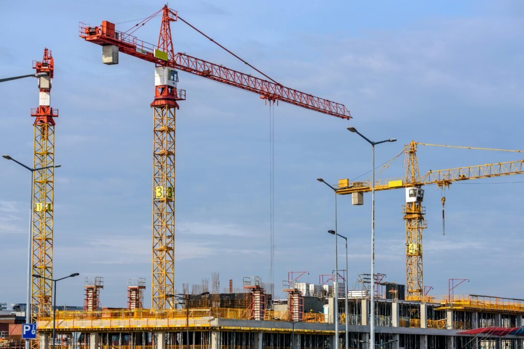 pexels-photo-224924-224924 Multiple tower cranes working on a large construction site with blue sky backdrop.