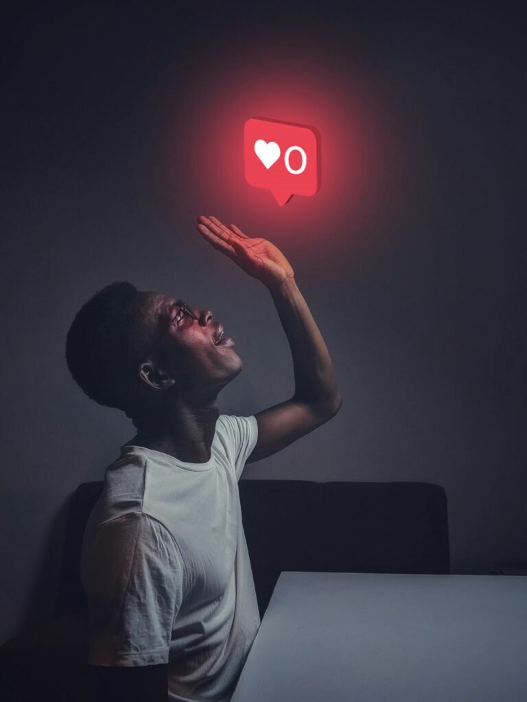 pexels-photo-3314294-3314294 A man sits indoors reaching towards a glowing social media notification icon.
