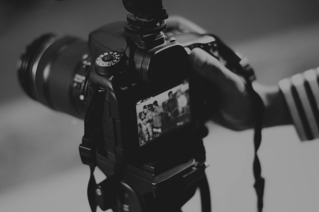 pexels-photo-403495-403495 Black and white image of a DSLR camera capturing people in focus, showcasing photography professionalism.