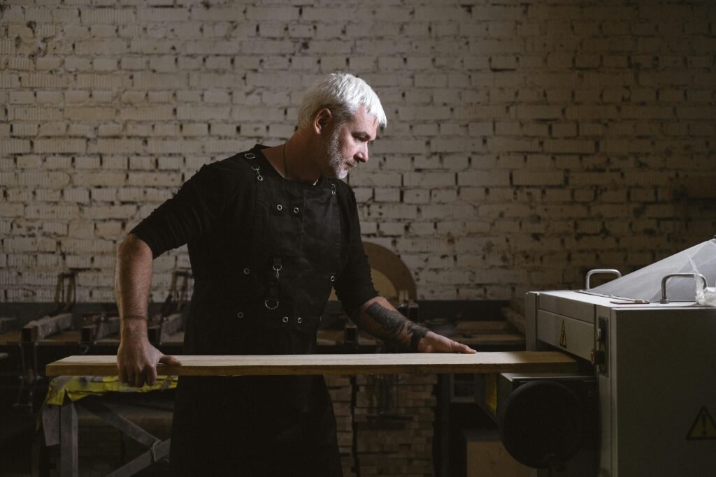 pexels-photo-5711693-5711693 A middle-aged craftsman focuses on woodworking with a lathe in a workshop.